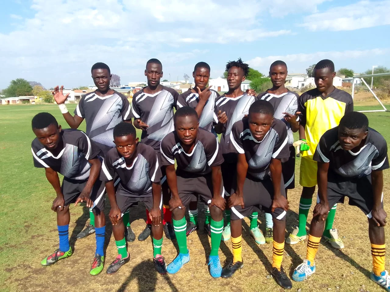 Magic Boys FC players standing together in their black and green match kit